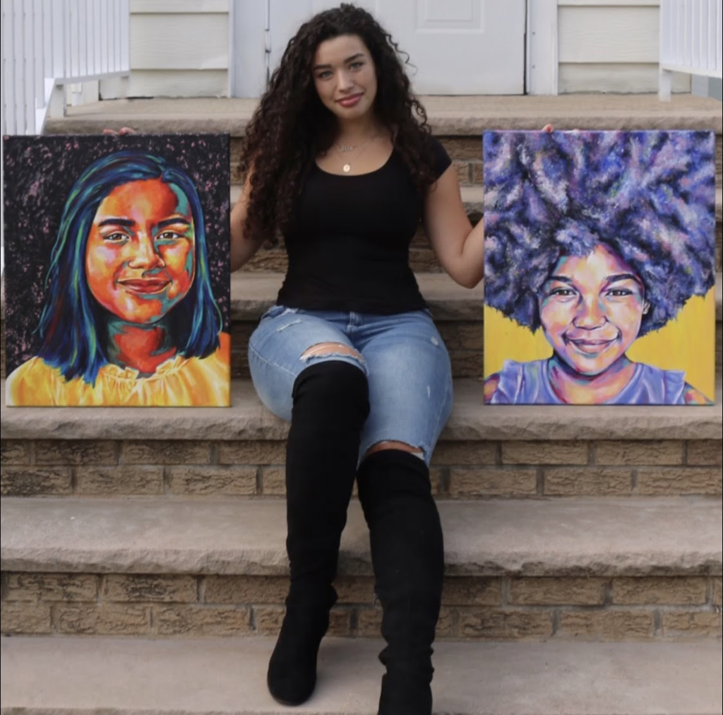 mia tomasino holding two colorful painted portraits