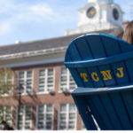 back of a blue adirondack chair with the letters TCNJ on it in yellow