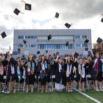 graduates in lions stadium toss their graduation caps
