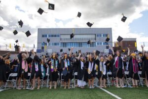 graduates in lions stadium toss their graduation caps